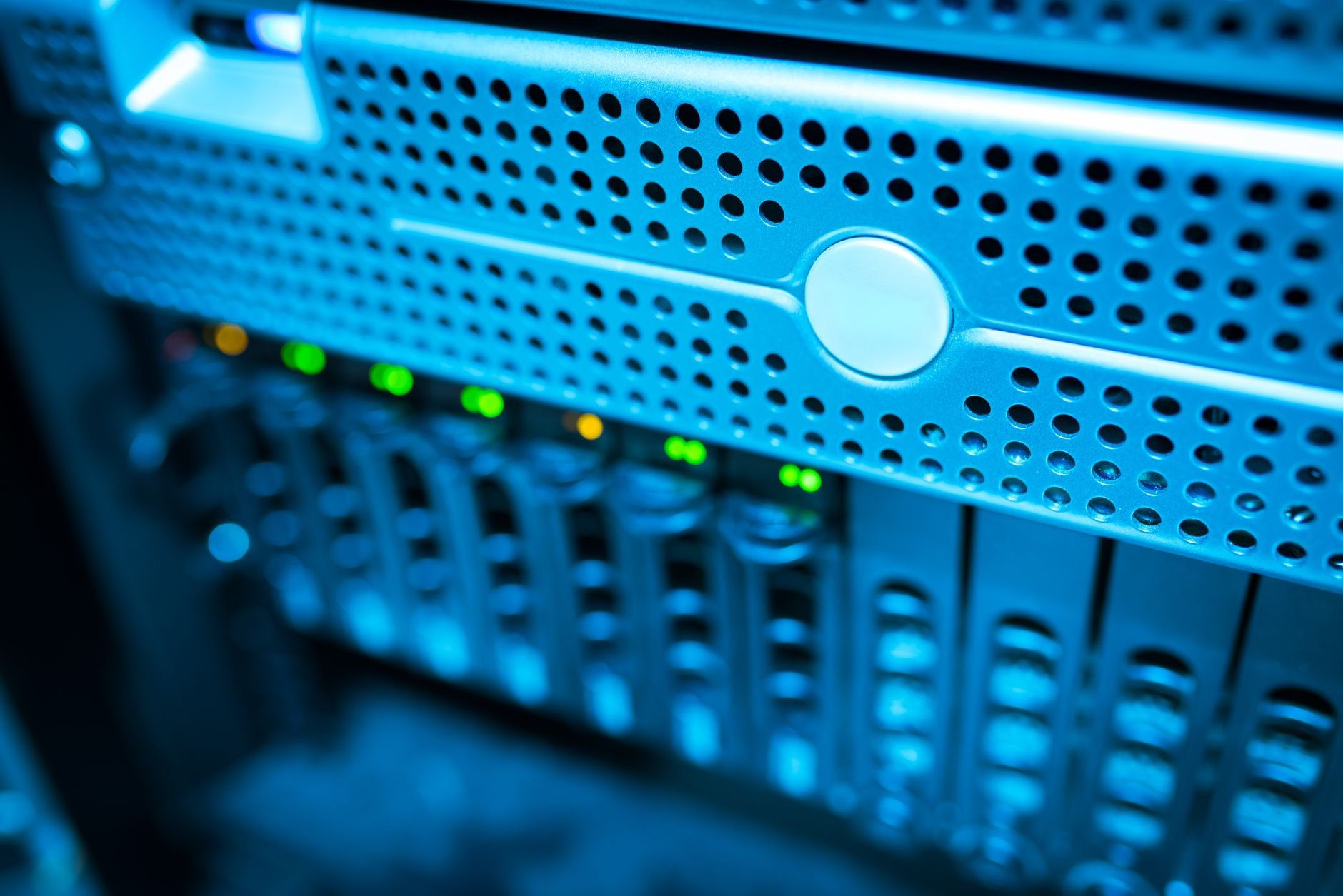 Close-up of a server front panel with rows of drive bays and green status lights in blue light
