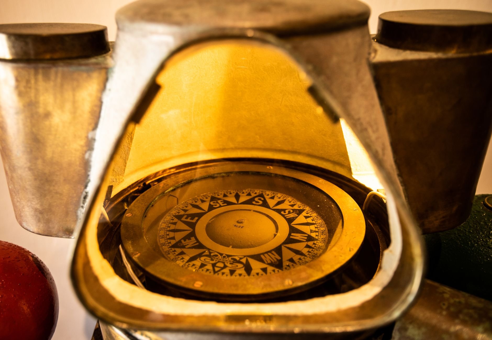 Close-up of a brass compass with a compass rose inside a metal housing