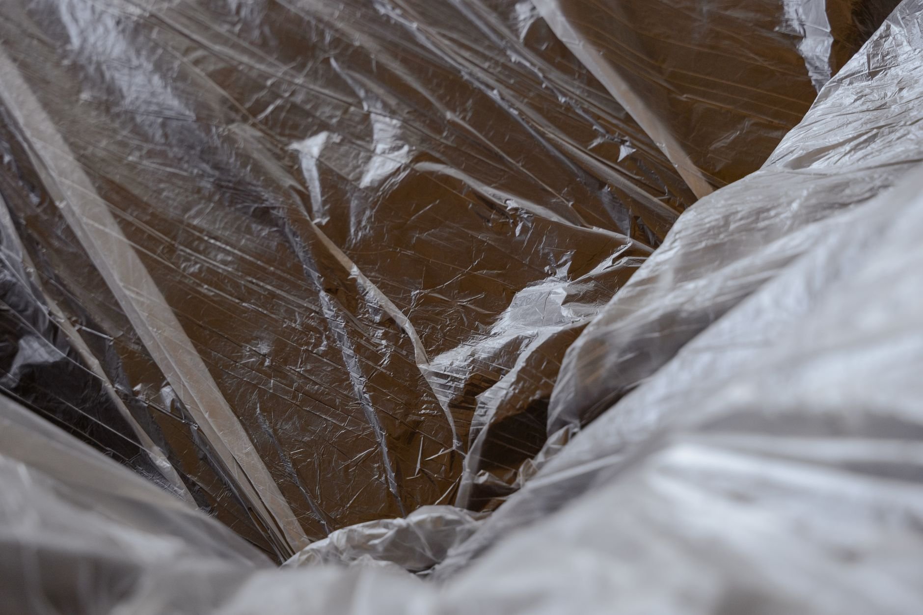 Close-up of crinkled clear plastic sheeting draped over a brown surface