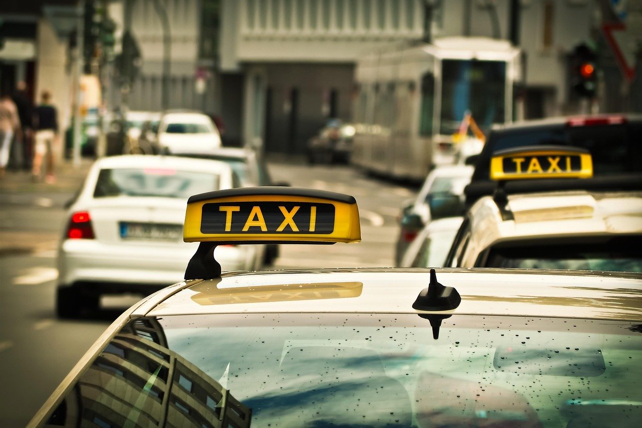 Yellow taxi roof signs on parked and moving cars on a city street